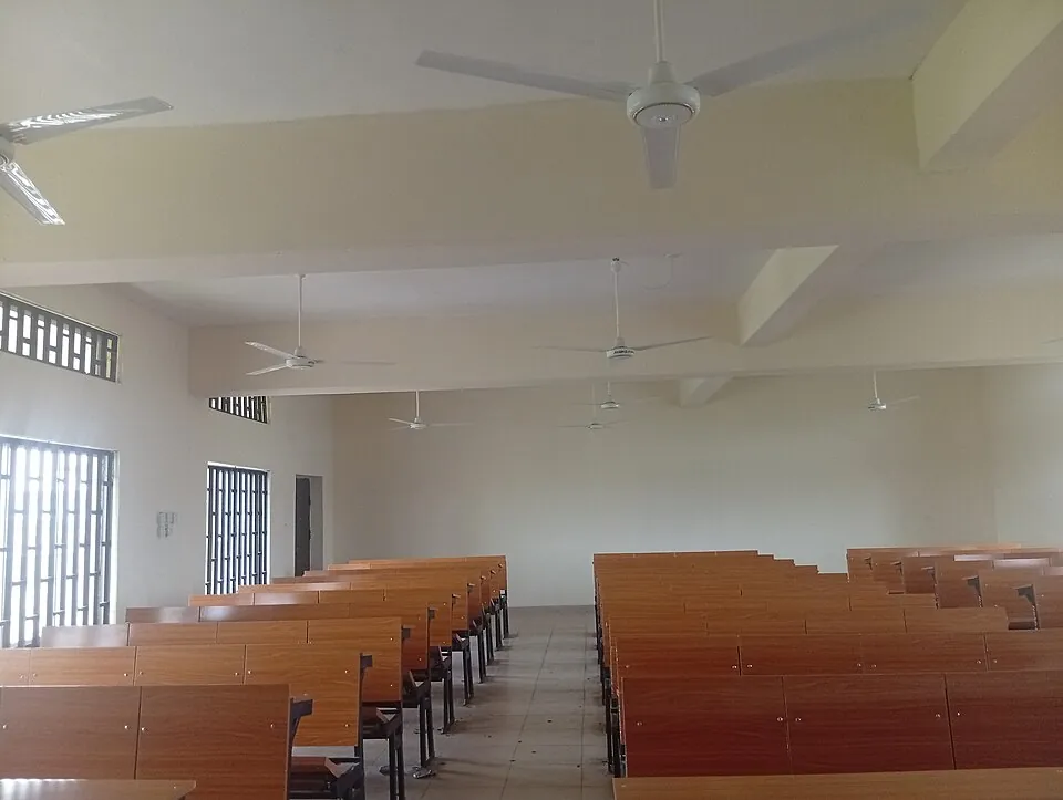 A ground-level view showing the clean wooden texture of the integrated student desks and benches inside an empty university classroom.