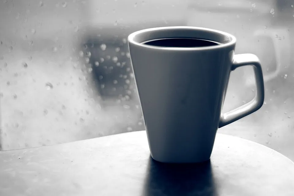 雨の日の窓辺に置かれたコーヒーのマグカップ
