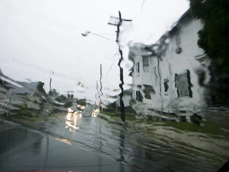 雨粒がついた車のフロントガラス越しの通り